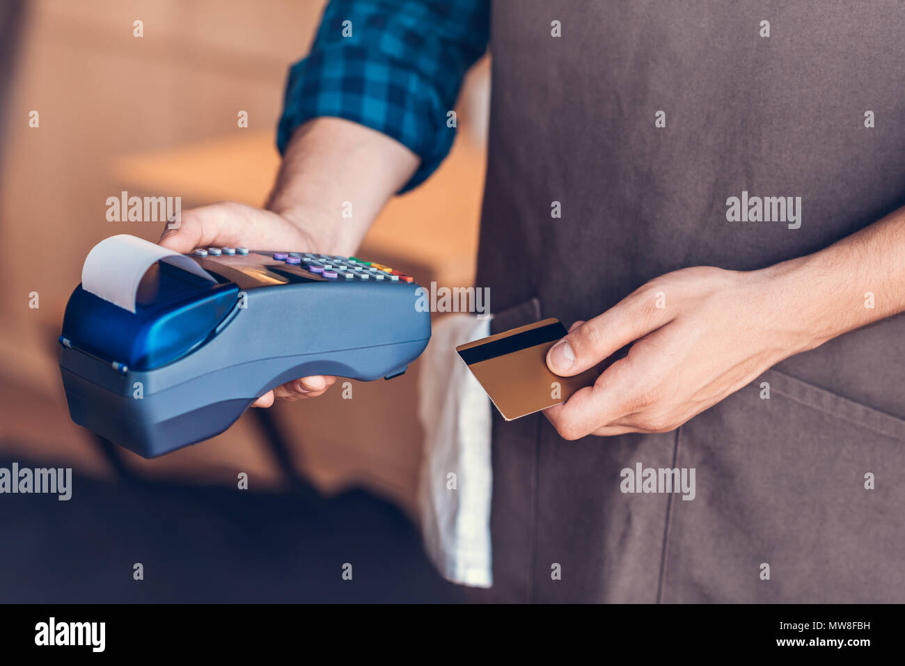 Vue partielle de barista holding credit card et lecteur de carte-clé en mains en cafe Banque D'Images