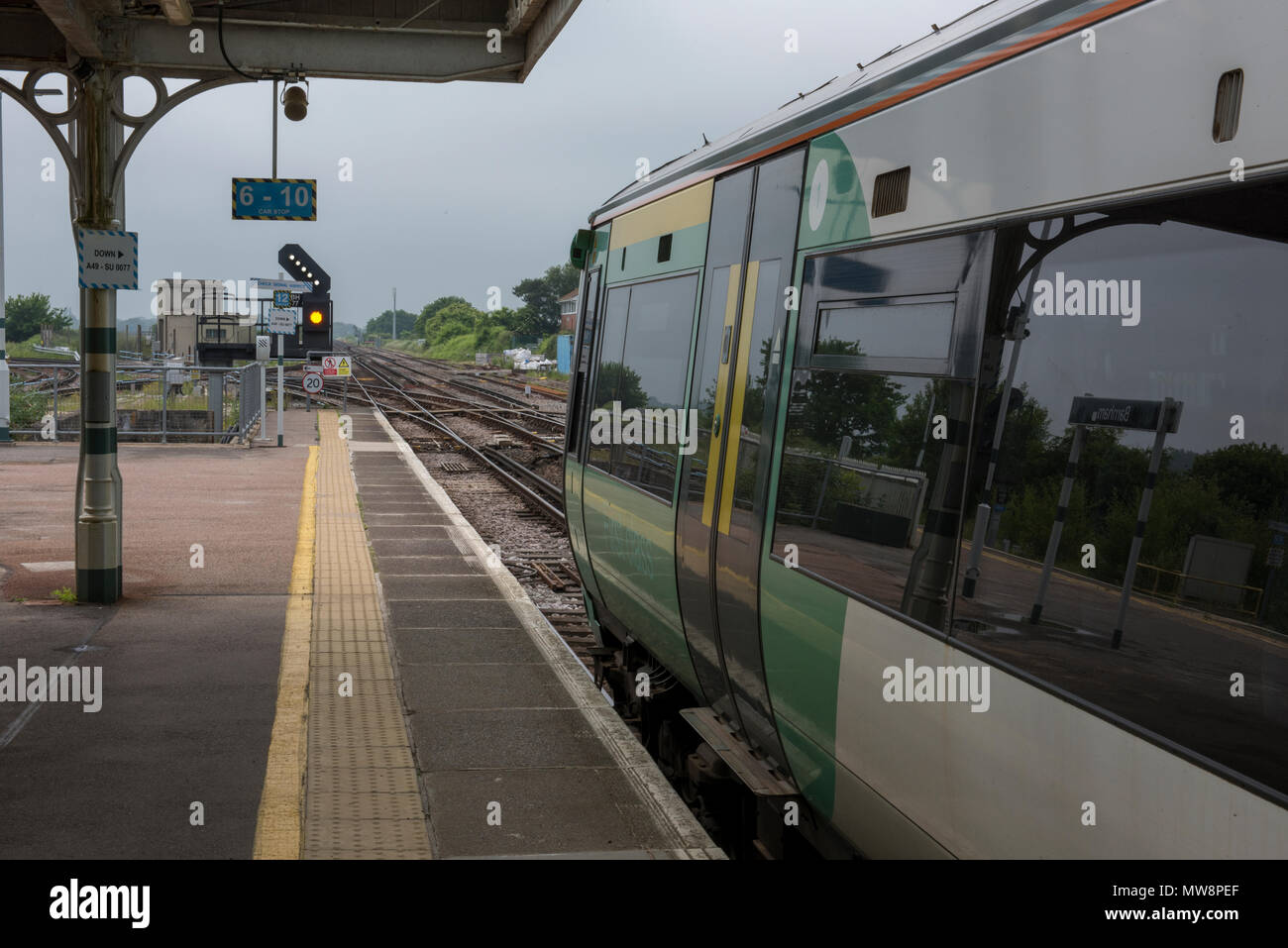 Un chemin de fer du sud ou train Thameslink govia dans la plate-forme à Barnham dans le Sussex en attente d'avancer le long de la piste à un signal jaune. Banque D'Images