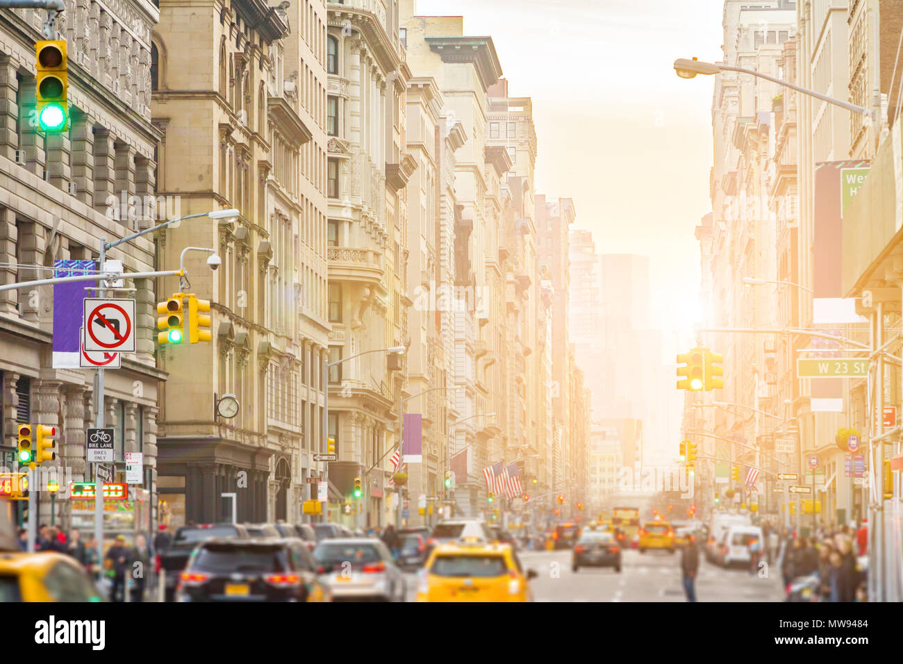 La lumière du soleil brille sur Broadway à New York City avec les gens et les voitures le long de la rue à travers Manhattan Banque D'Images