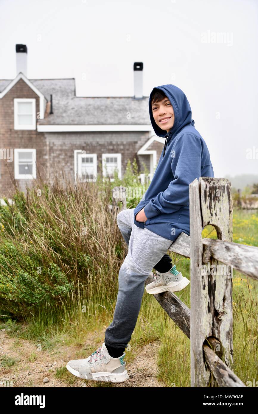 Adolescent assis sur une vieille clôture en bois sur l'île de Cape Cod, Massachusettes Banque D'Images
