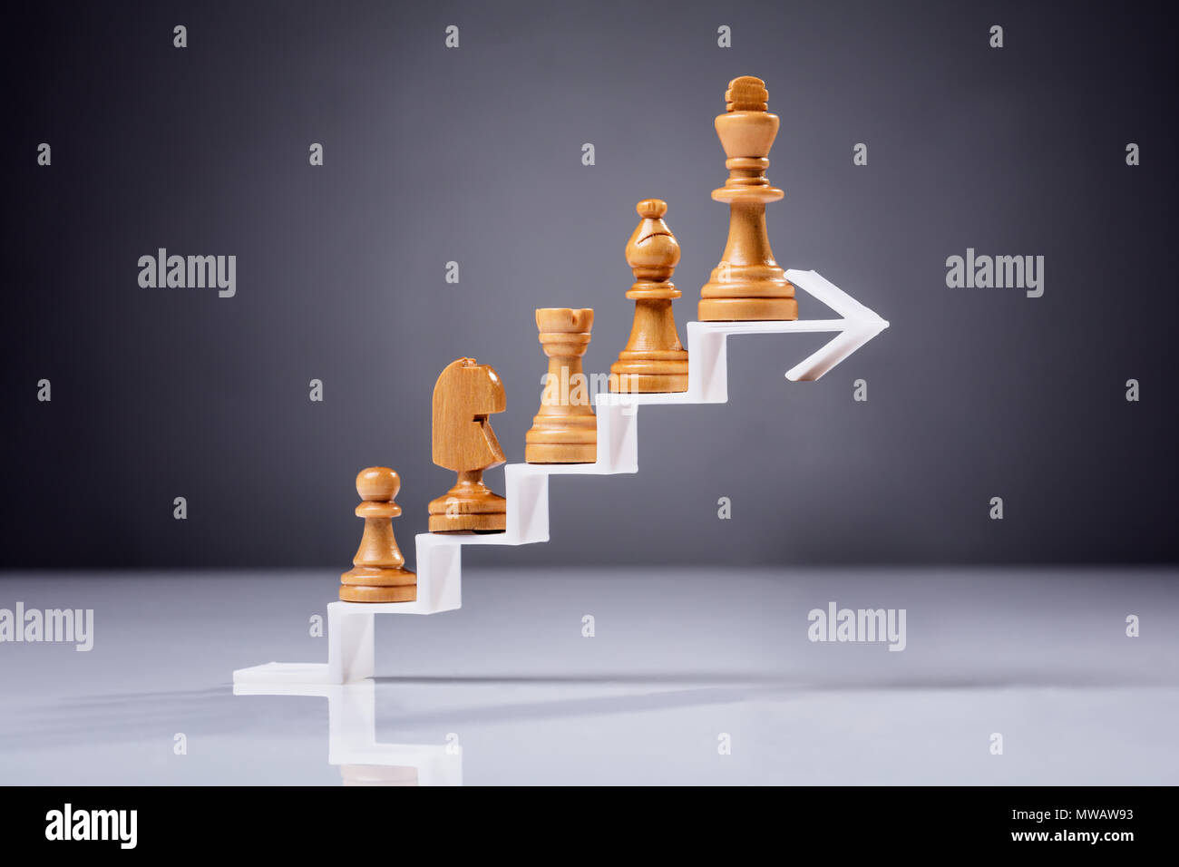 Pièce d'échecs en bois sur l'augmentation de flèche zigzag contre fond gris Banque D'Images