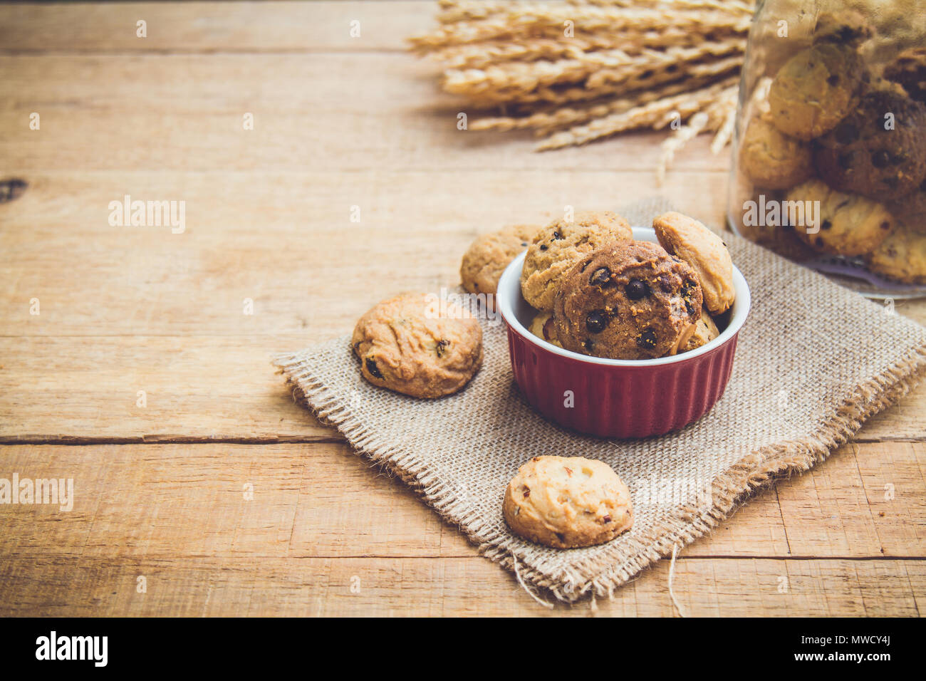 Cookie dans red cup sur le chanvre sac sur table en bois avec copie espace. vintage tone. Focus sélectif. Banque D'Images