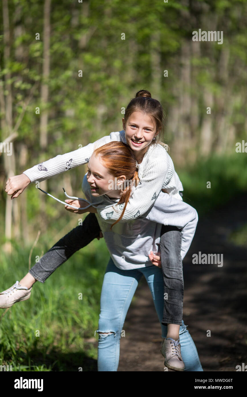 Deux soeurs filles adolescents amis équitation les uns les autres s'amuser dans le parc à l'été. Banque D'Images