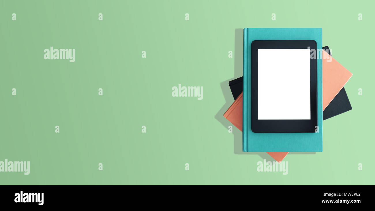 Vue du dessus de l'e-book reader sur pile de livres sur le bureau vert Banque D'Images