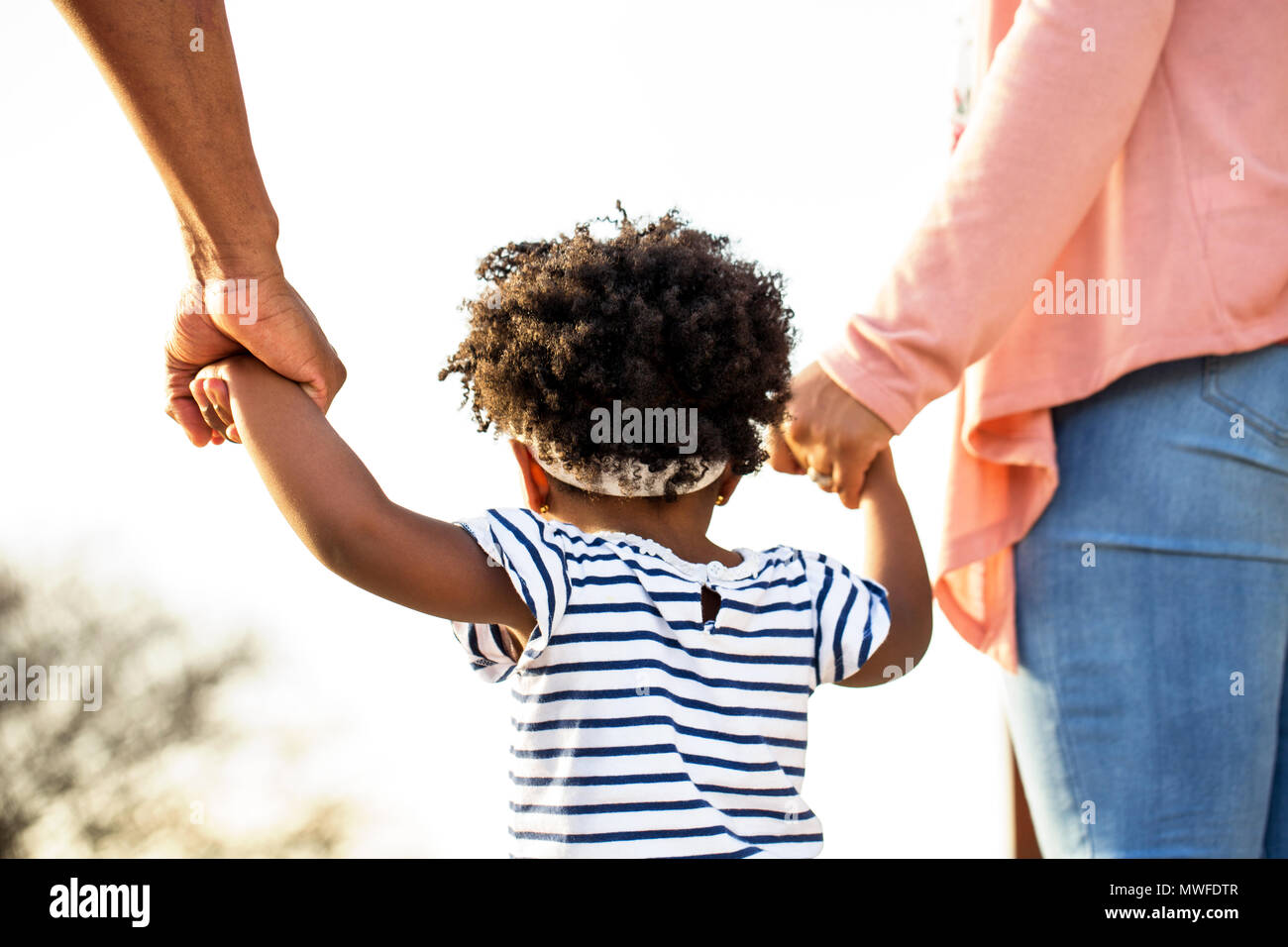 Little girl holding hands with parents. Banque D'Images