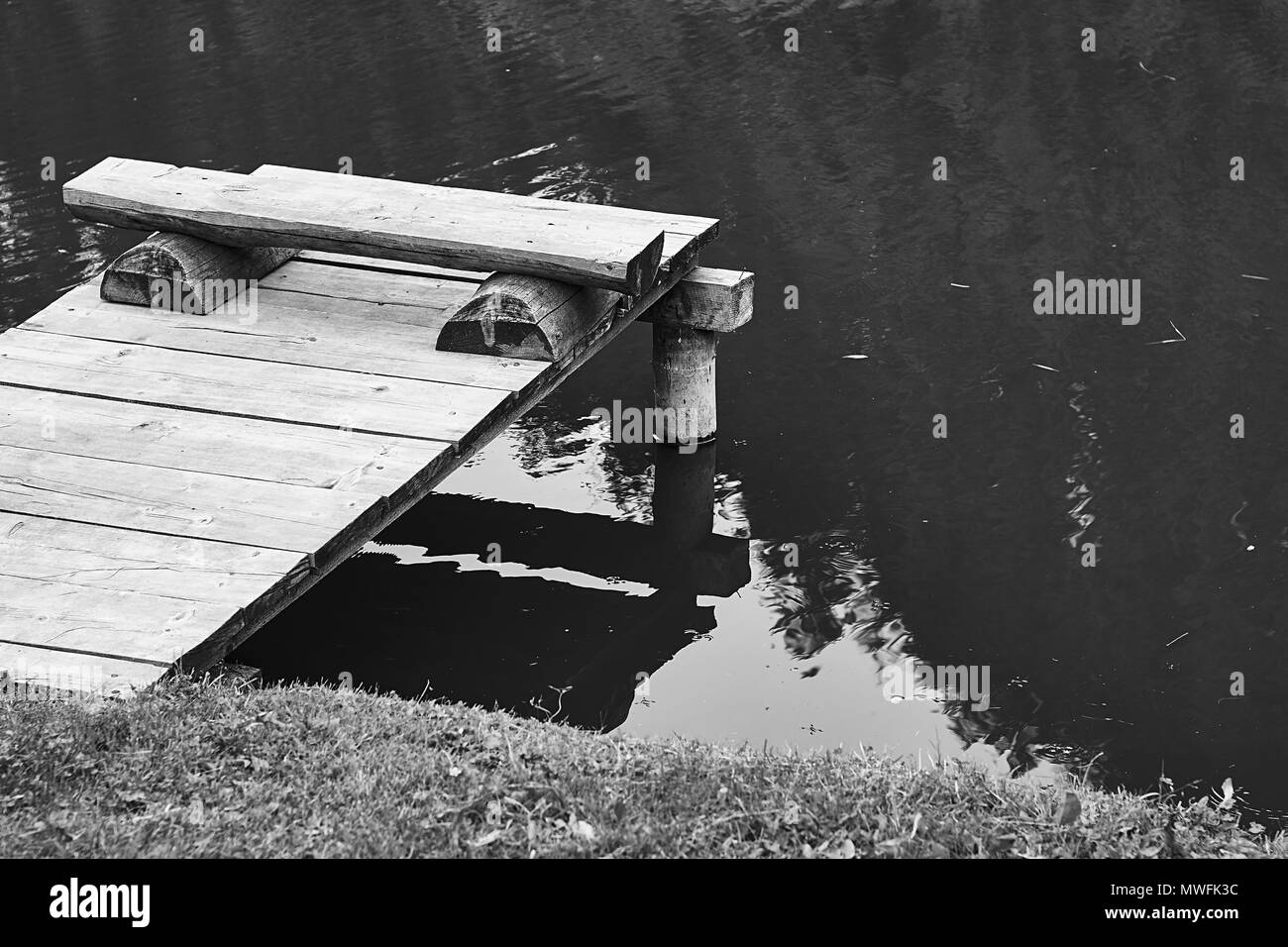 Banc de pêche confortable sur une jetée en bois au bord d'un étang ou un lac calme en été nountains Banque D'Images