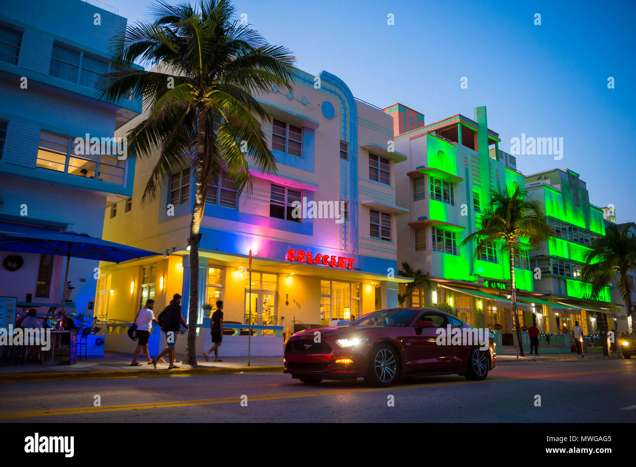 MIAMI - janvier 08, 2018 : Un convertible rouge passé lecteurs hôtels art déco emblématique et des enseignes au néon sur Ocean Drive à South Beach de nuit. Banque D'Images