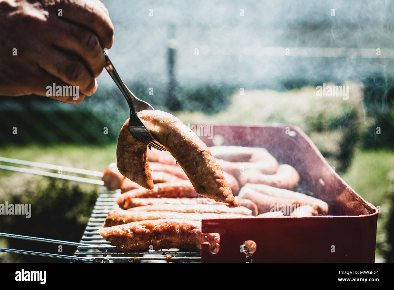 Tirant les saucisses sur le grill. L'homme tire le fini de saucisses sur le grill. Passer du temps avec la famille au grill. Las Palapas Social Banque D'Images