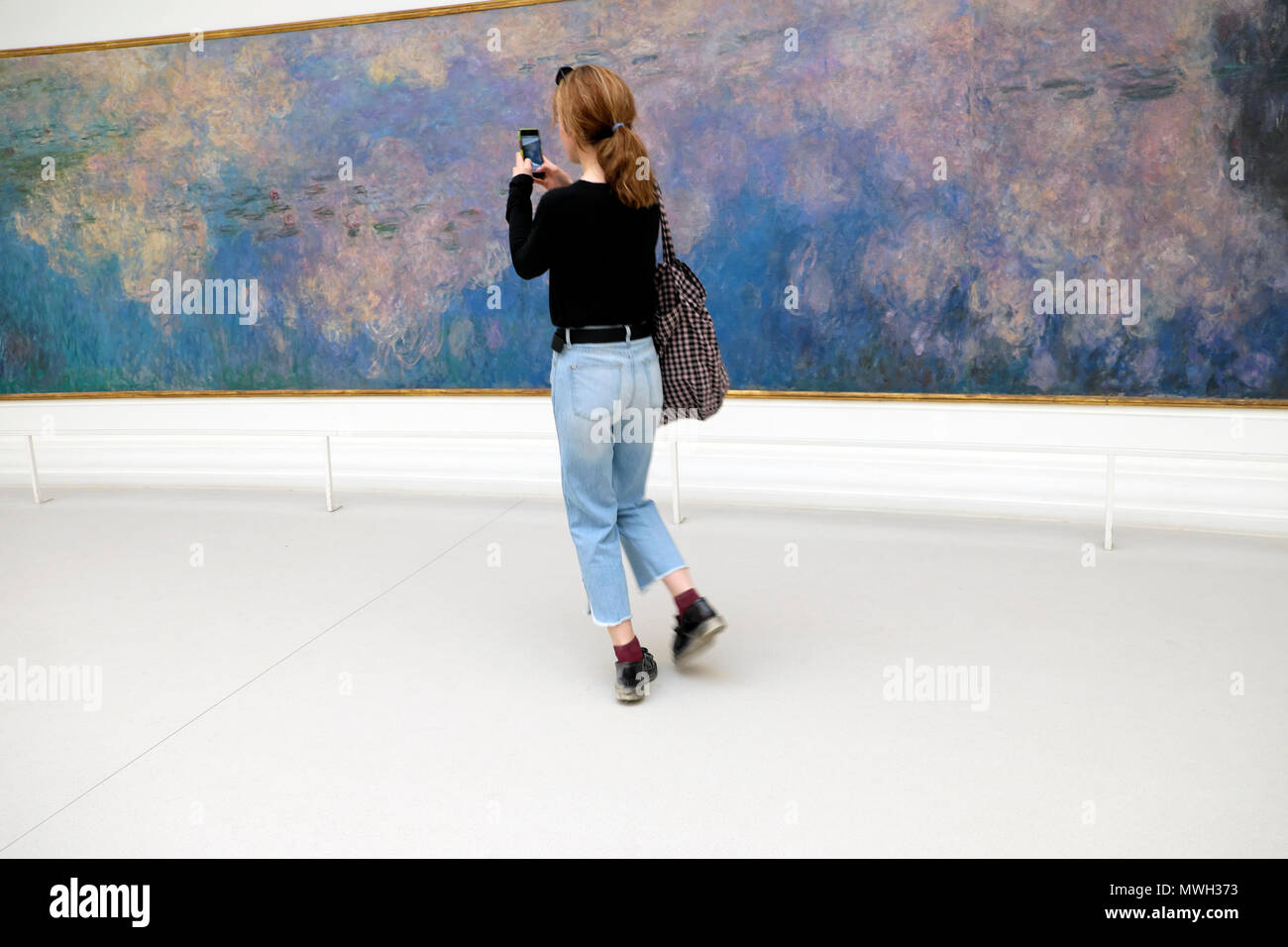 Visiteur photographiant Claude Monet Nymphéas Nymphéas peinture au Musée de l'Orangerie Jardin des Tuileries avec mobile phone in Paris France KATHY DEWITT Banque D'Images