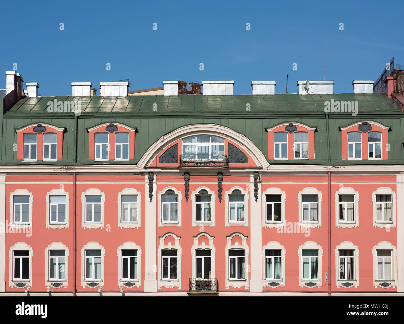 Façade d'un vieux bâtiment avec un toit mansardé. Fenêtres et murs roses Banque D'Images