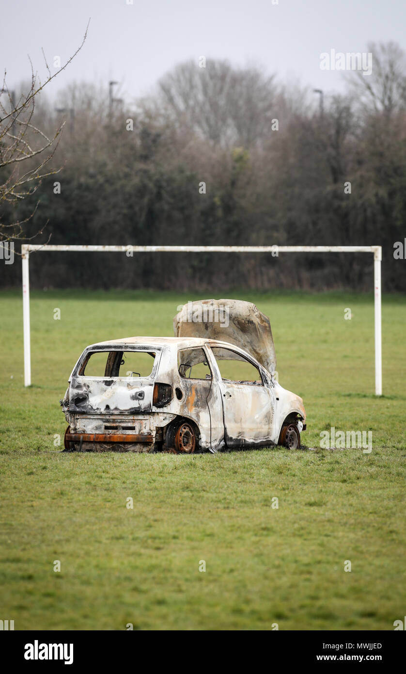 Burnt Out voiture volée abandonnés sur un terrain de football de la communauté à côté d'un conseil en immobilier Hampshire Banque D'Images