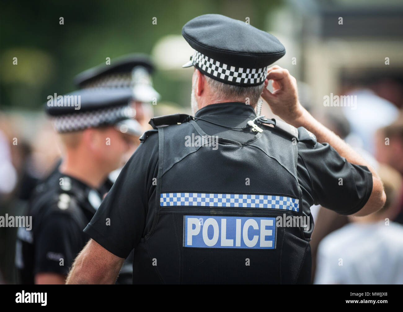 Agents de service lors d'un événement public dans le Hampshire, avec un policier à l'écoute de sa radio de police dans son oreille Banque D'Images