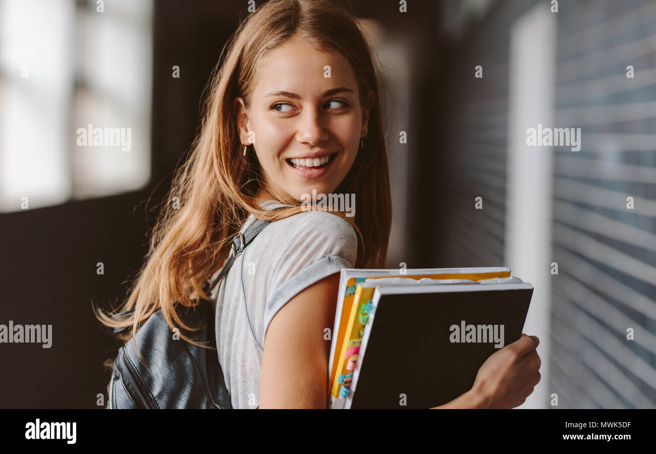 Vue arrière de la belle étudiante marche à travers le couloir du collège à l'arrière et de sourire. Fille de la classe. Banque D'Images