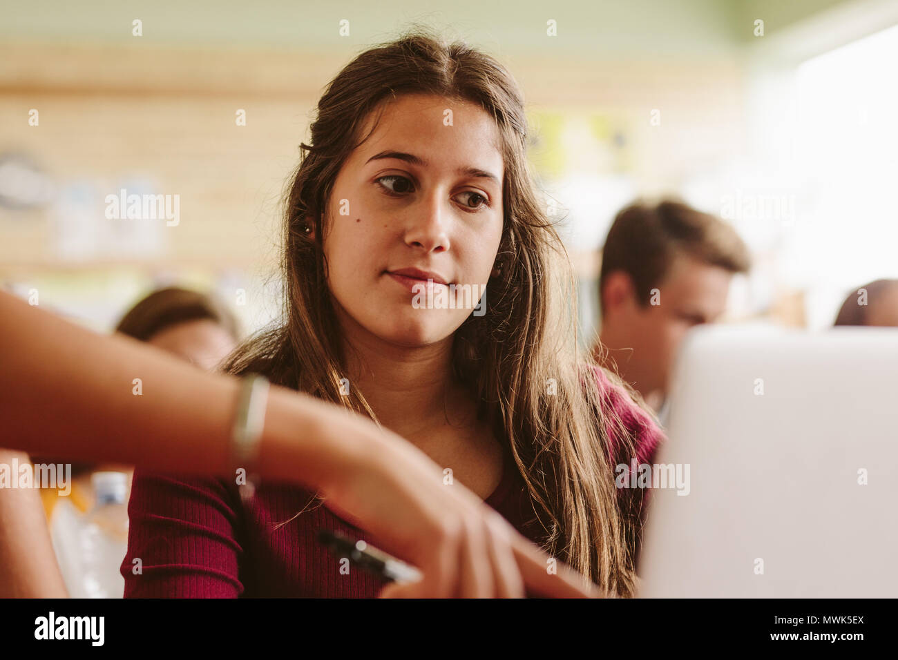 Close up of belle étudiante à l'écoute de l'instruction de l'enseignant. Femme regardant un écran d'ordinateur portable avec maître de pointage. Banque D'Images