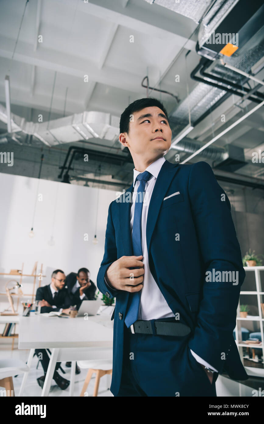 Handsome asian businessman with blurred collègues on background Banque D'Images