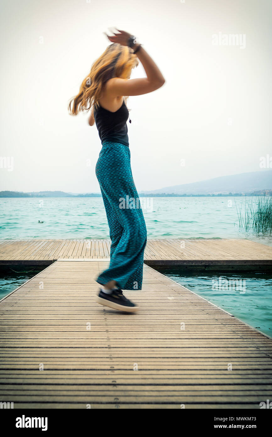 Jeune fille dansant sur le quai, le lac de Pusiano, Lecco, Italie Banque D'Images