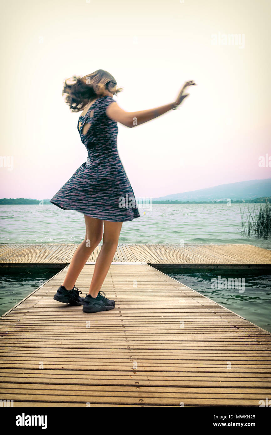 Jeune fille dansant sur le quai, le lac de Pusiano, Lecco, Italie Banque D'Images
