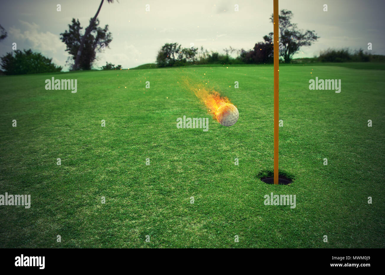Fiery balle de golf près du trou dans un champ d'herbe Banque D'Images