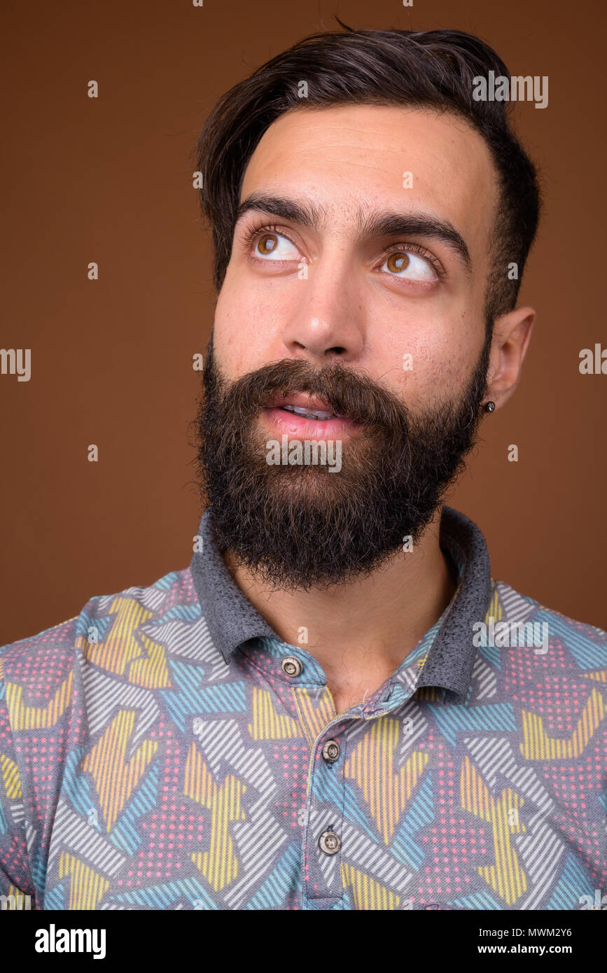 Beau jeune homme persan barbus contre fond brun Banque D'Images