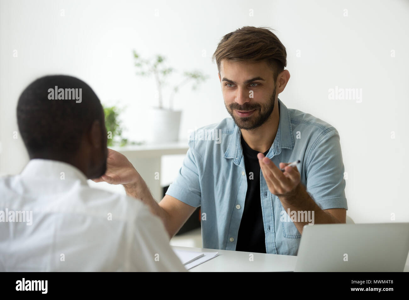 Smiling Caucasian worker talking to black in office Banque D'Images