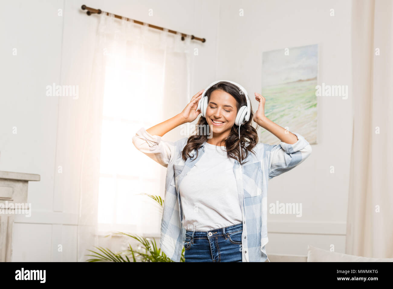 Happy young woman wearing headphones listening music at home Banque D'Images