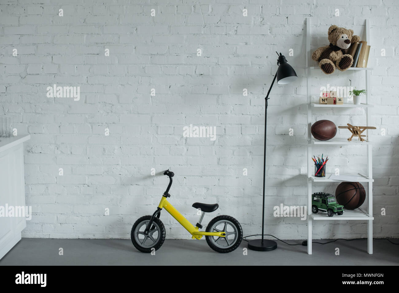 Vue rapprochée de la chambre enfantine vide avec balance bike contre white brick wall Banque D'Images