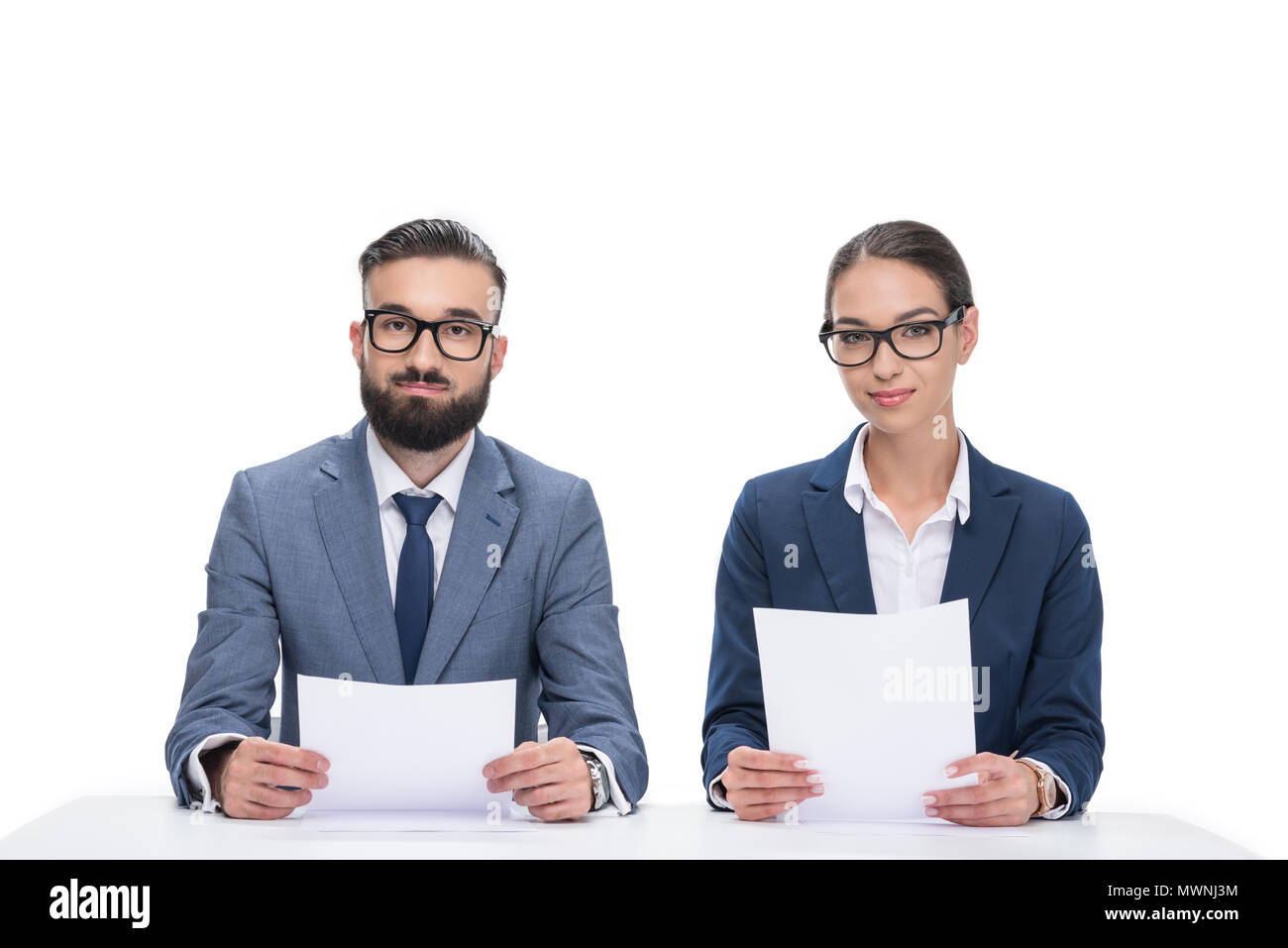 Deux journalistes avec papiers assis à table et looking at camera, isolated on white Banque D'Images
