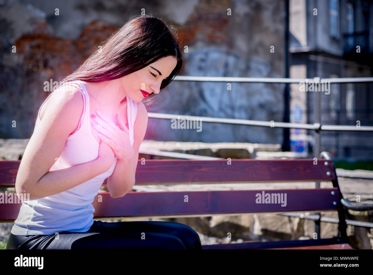 Woman is holding sa poitrine. crise cardiaque. Park et à l'extérieur. Par rapport au travail, fatigué, malade. Banque D'Images