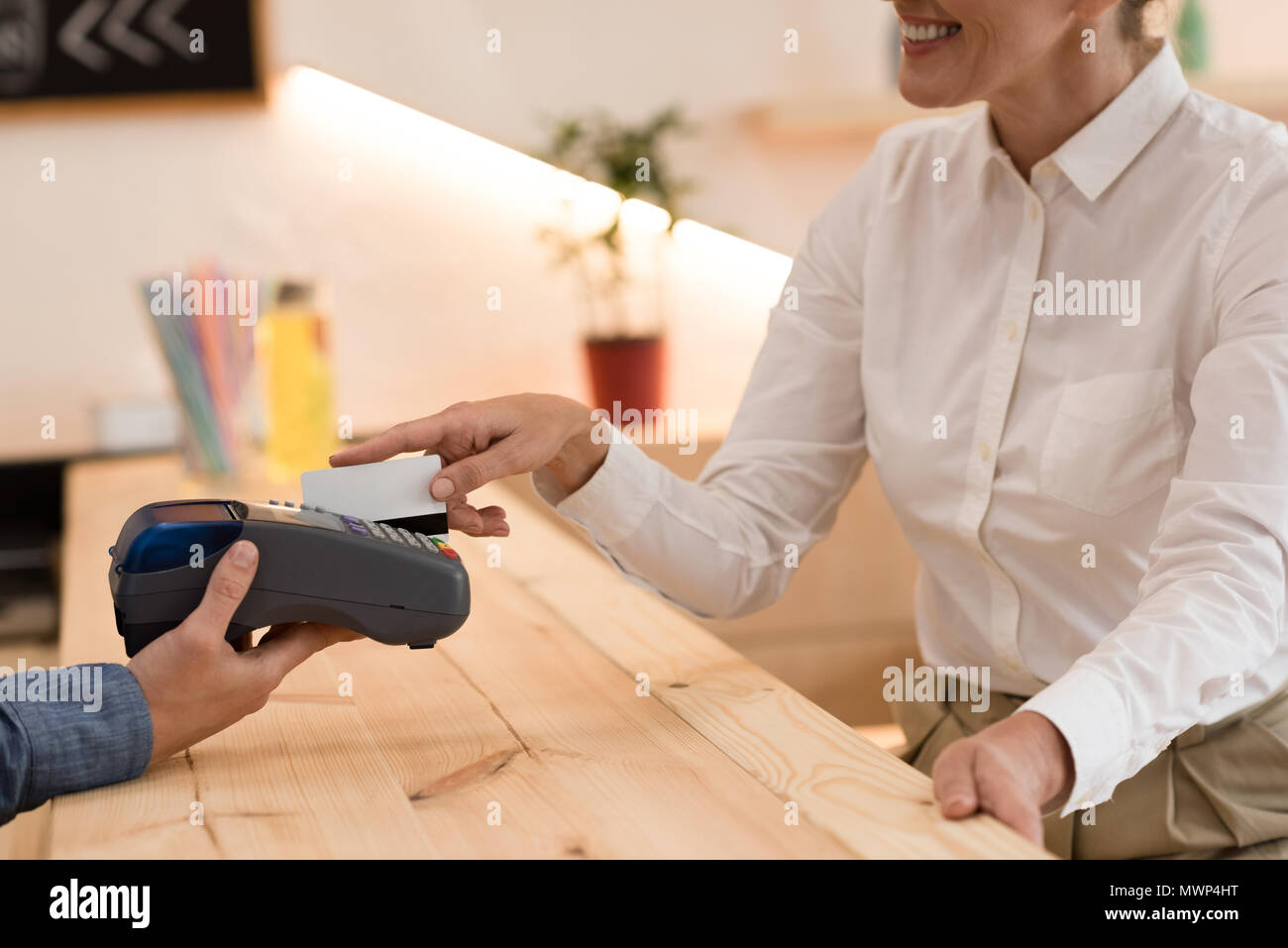 Vue partielle de smiling woman making paiement avec carte de crédit au cafe Banque D'Images