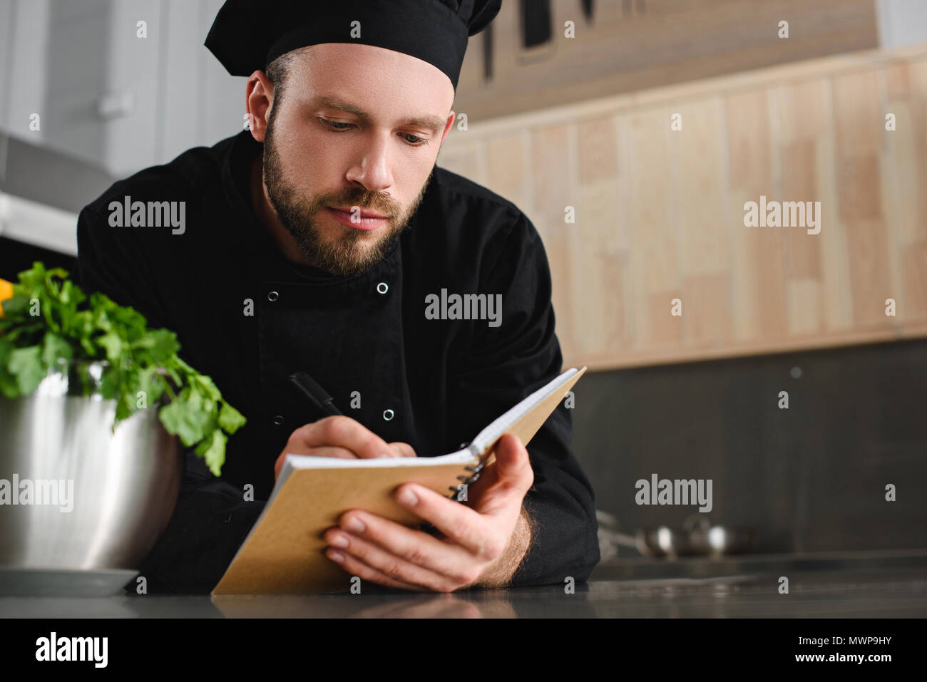 Beau chef d'écrire à l'ordinateur portable nouvelle recette de cuisine restaurant Banque D'Images