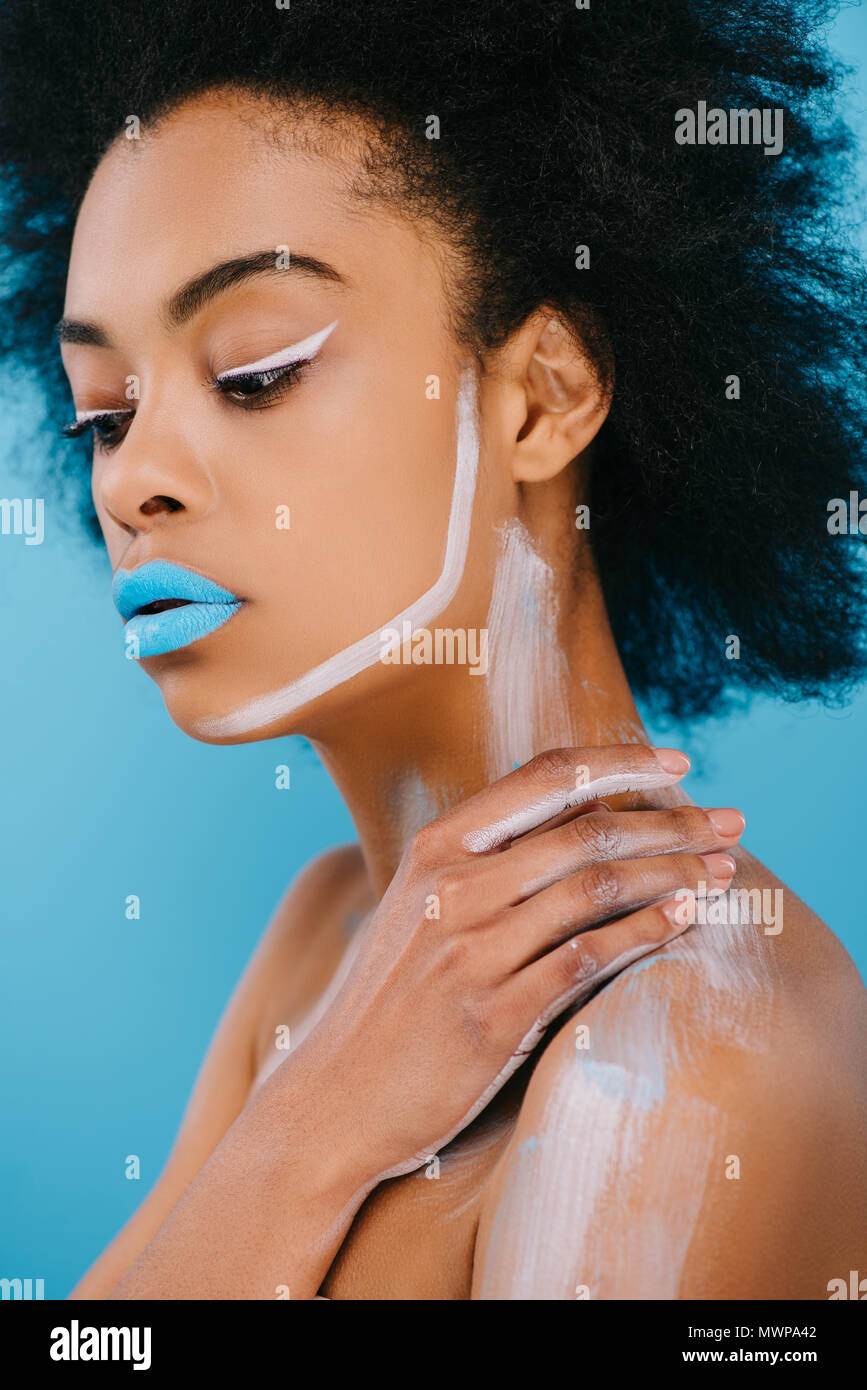 Jeune femme afro avec maquillage créatif et lèvres bleu sur bleu isolé Banque D'Images