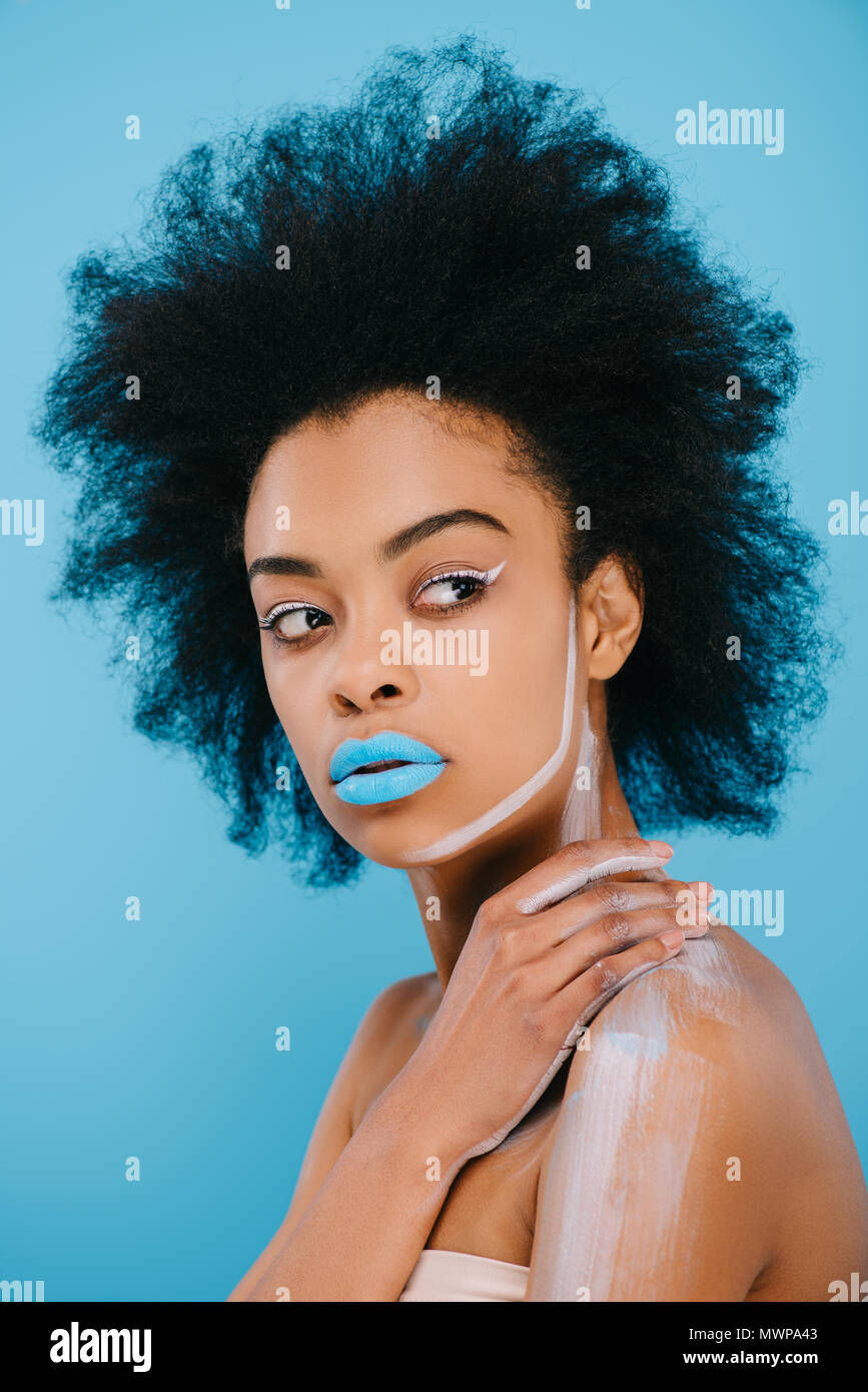 Jolie jeune femme avec maquillage créatif et lèvres bleu sur bleu isolé Banque D'Images
