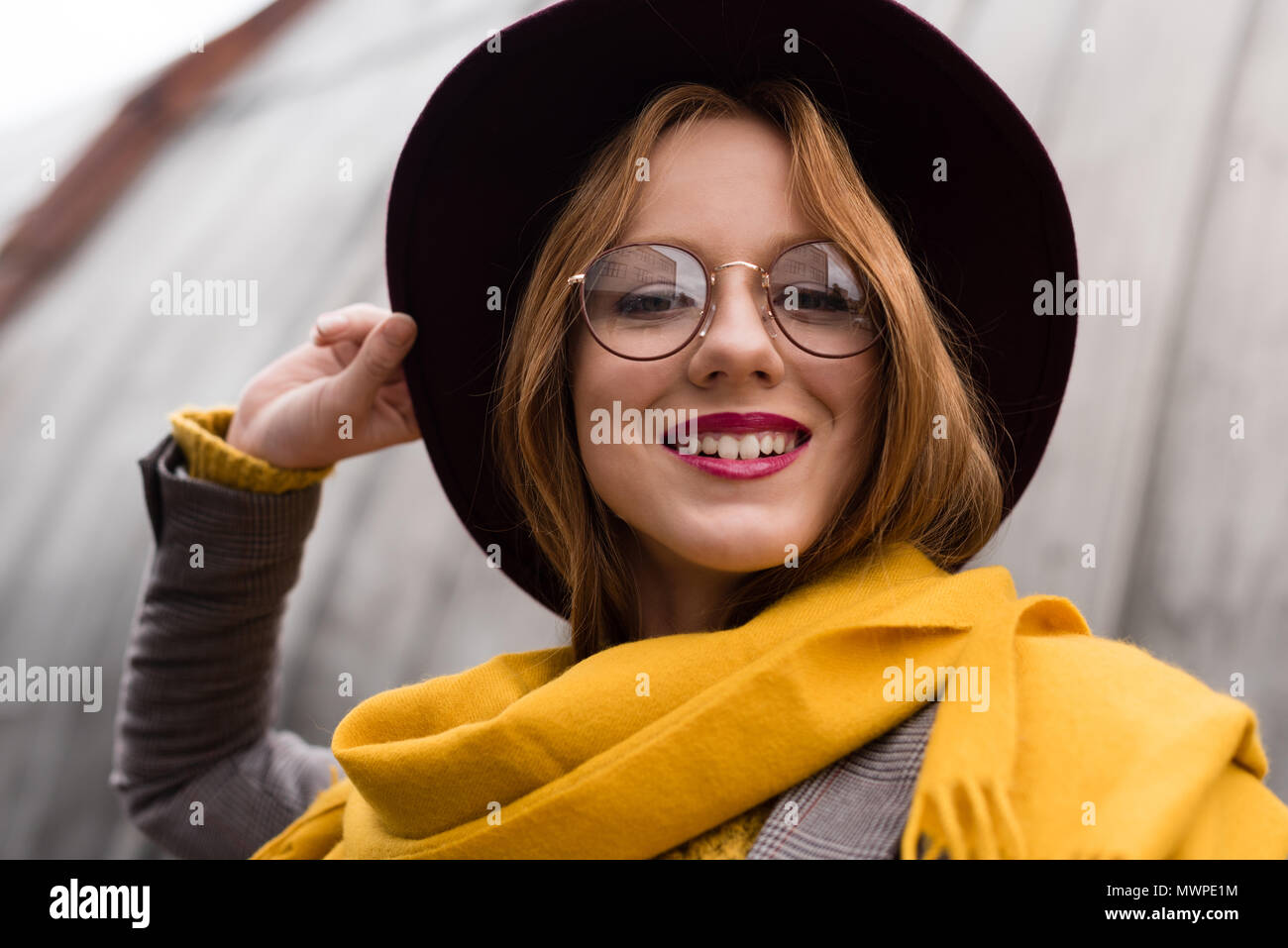 Belle jeune fille rousse souriant élégant dans les lunettes, écharpe jaune  et chapeau fedora Photo Stock - Alamy