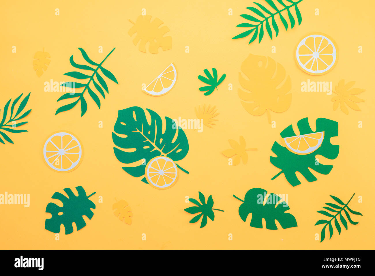 Motif feuilles tropicales. Green monstera et fougères avec l'orange et les tranches de citron sur un fond jaune vif. Vacances d'été avec du papier craft concept fruits Banque D'Images