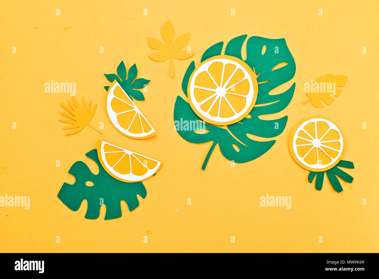 Motif feuilles tropicales. Green monstera et fougères avec l'orange et les tranches de citron sur un fond jaune vif. Vacances d'été avec du papier craft concept fruits Banque D'Images