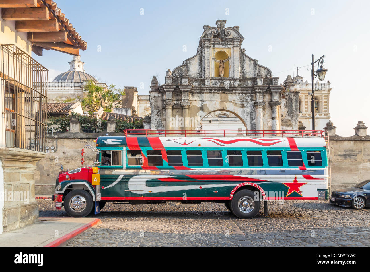 Un bus coloré typique poulet peint en passant à la porte d'entrée de l'église San Francisco à Antigua, Guatemala, l'UNESCO, l'Amérique centrale Banque D'Images