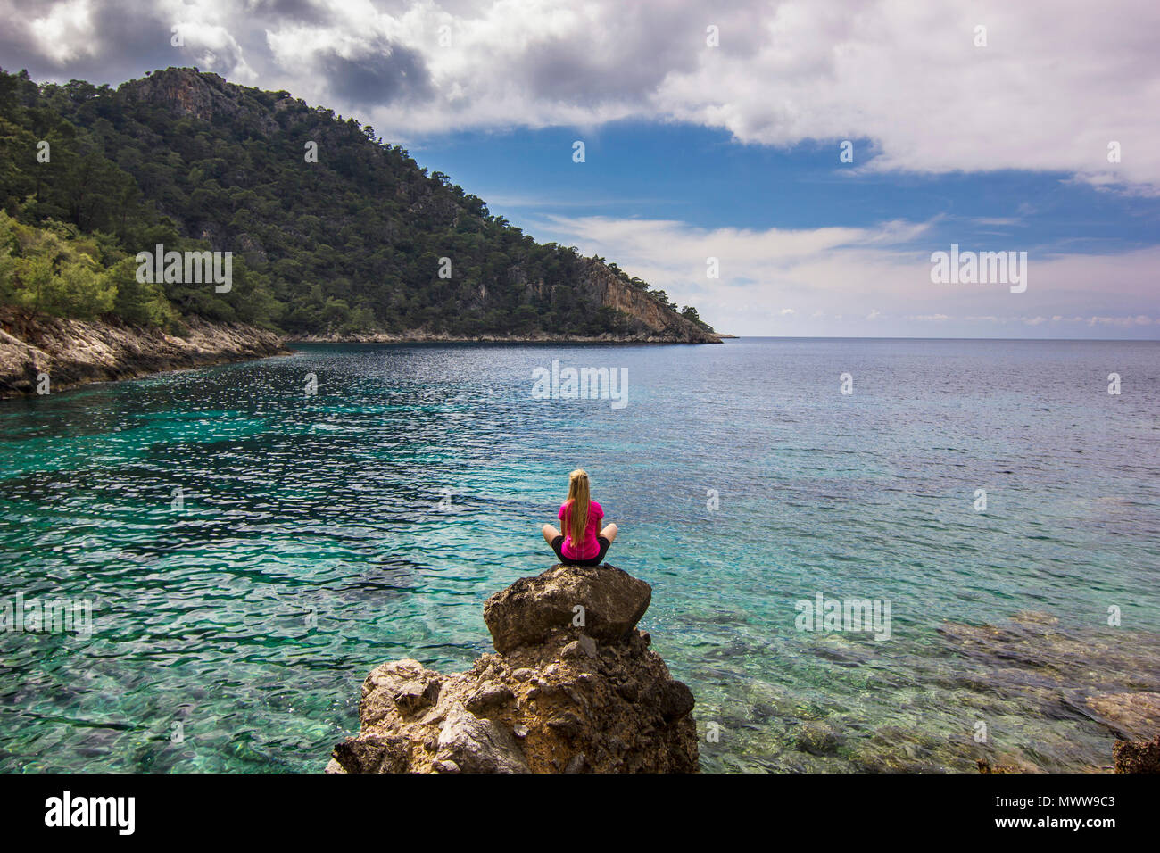 Fille assise sur une falaise de montagnes au-dessus de la mer méditerranée avec belle vue Banque D'Images