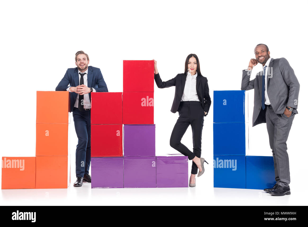 Les gens d'affaires multiethniques souriant debout près de blocs colorés isolé sur blanc, concept d'équipe Banque D'Images