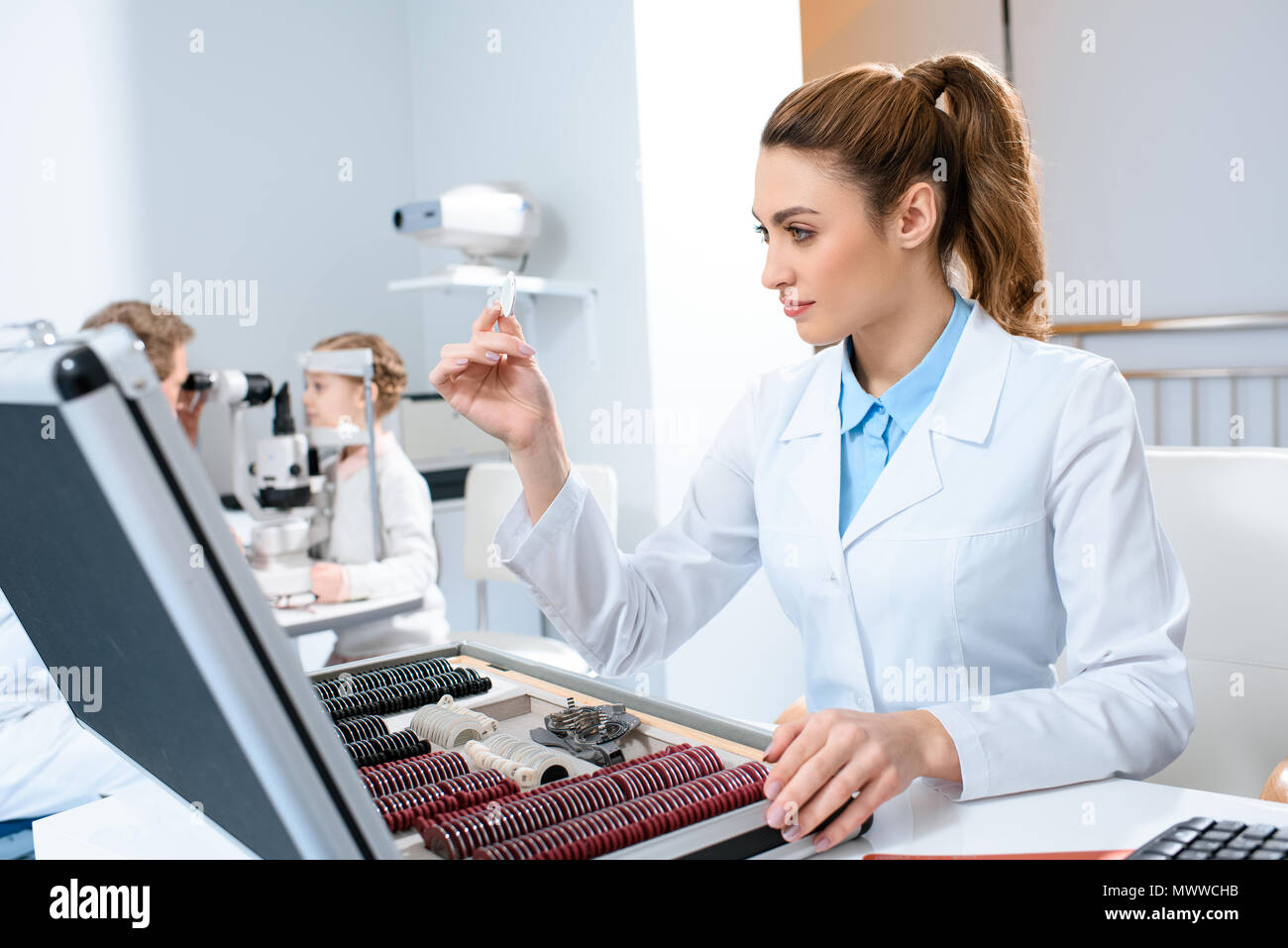 Ophtalmologiste femelle avec des objectifs pour le procès le châssis tout en collègue examinant kid avec test de champ visuel Banque D'Images