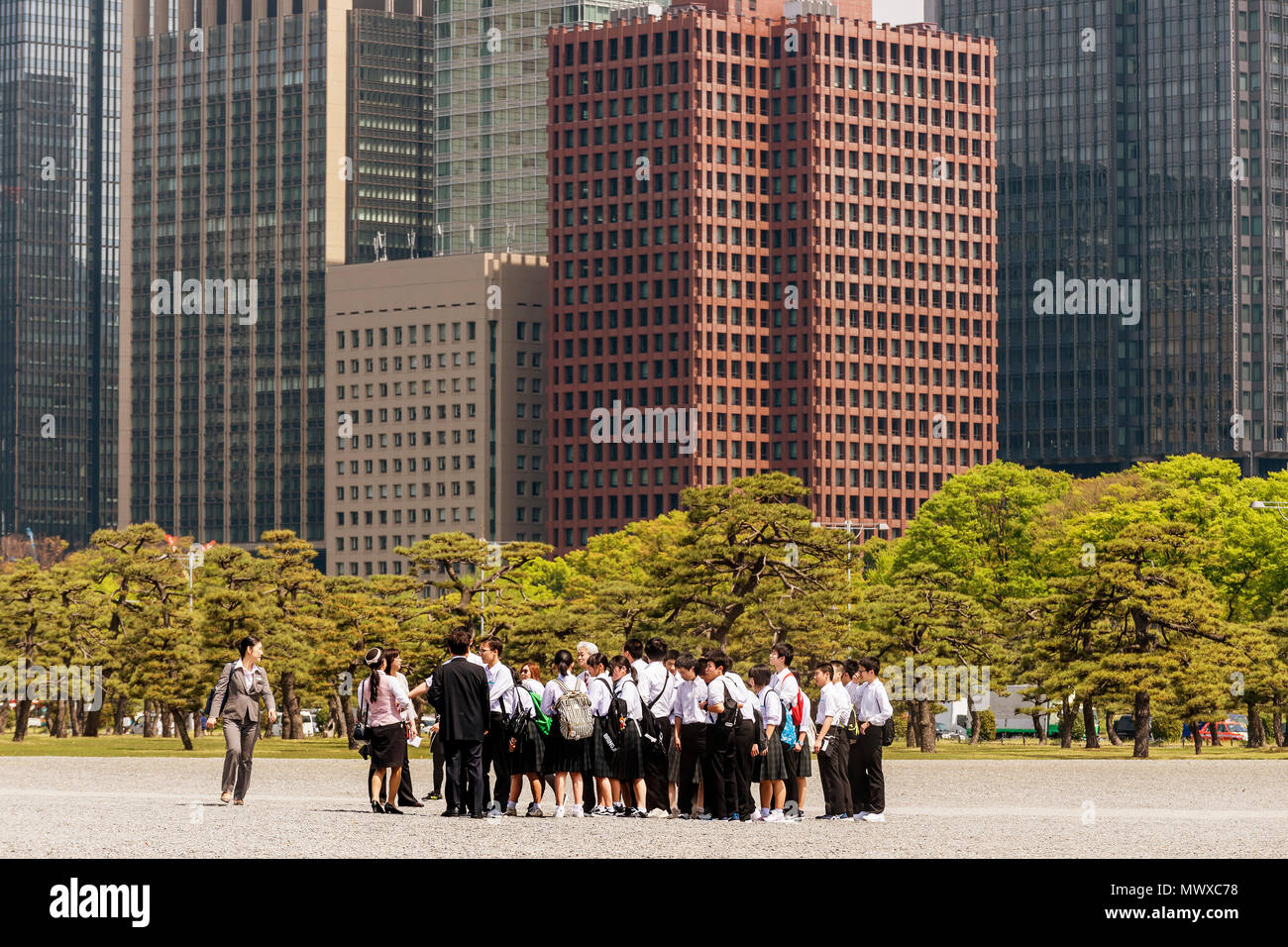 Groupe scolaire japonais visitant le Palais Impérial à Tokyo avec les gratte-ciel de Chiyoda, le Japon dans l'arrière-plan Banque D'Images