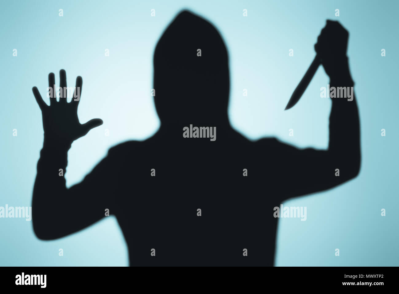 Scary ombre de personne dans le capot holding knife sur bleu Banque D'Images