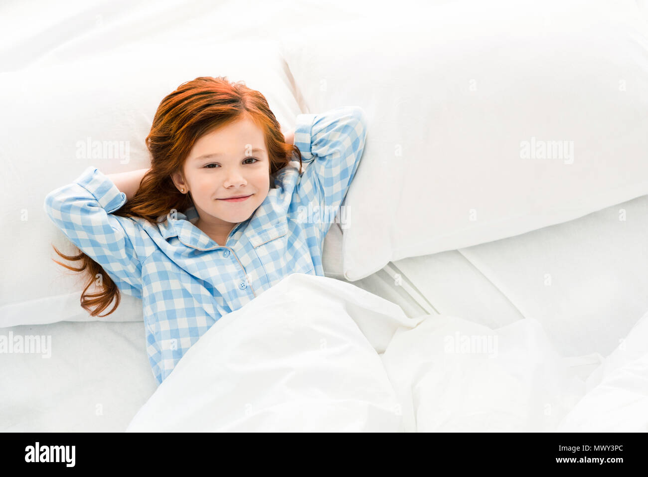 Adorable petit enfant en pyjama dans mon lit et smiling at camera Banque D'Images