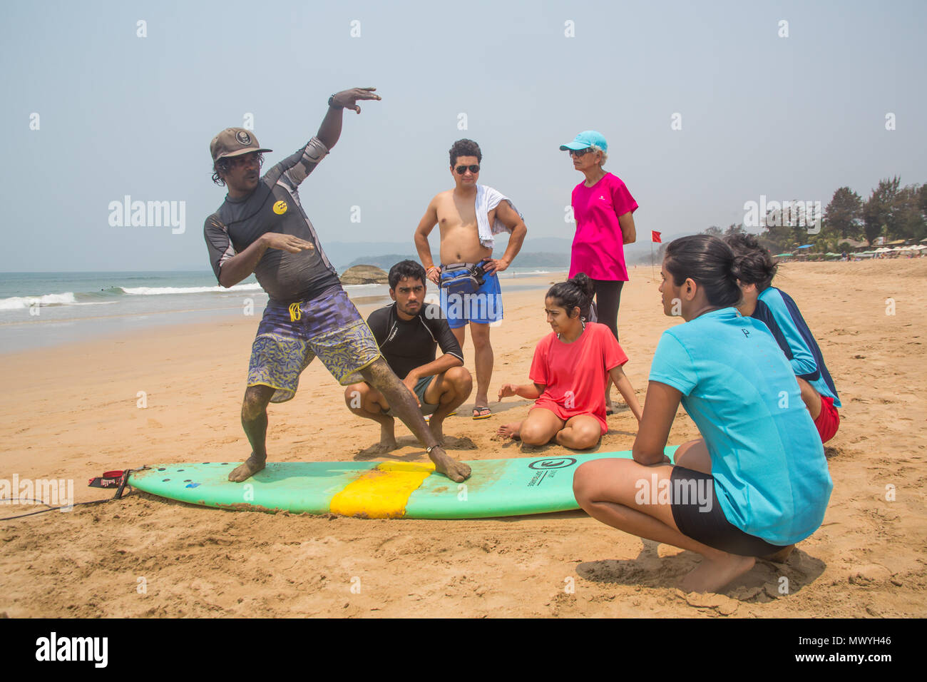 Velu, fondateur de Aloha Surf Inde, montrant comment certains élèves de se tenir debout sur une planche de surf sur la plage d'Agonda. Banque D'Images