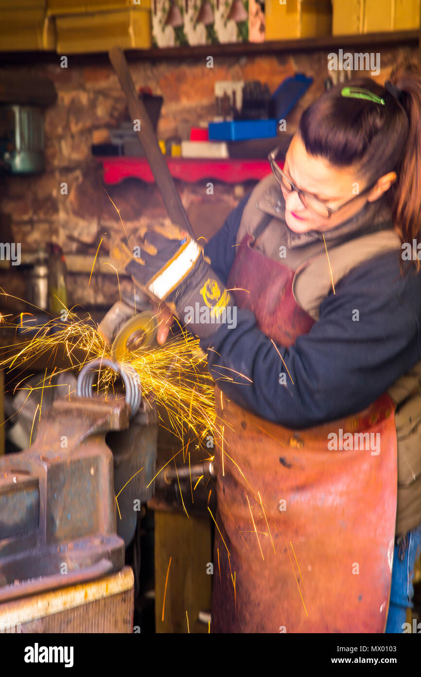 Femme forgeron au travail dans l'ancienne forge à Cockington Forge dans le Devon. Banque D'Images
