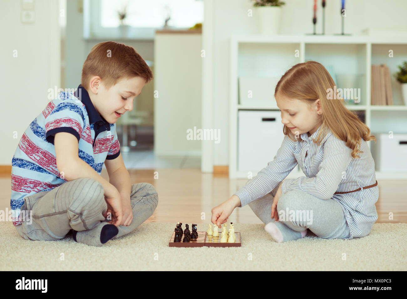 Deux petits enfants jouant aux échecs à la maison émotionnellement Banque D'Images