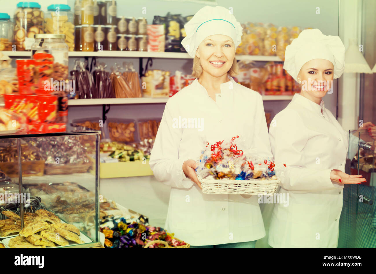 Le personnel souriant femmes offrant des bonbons dans la confiserie locale Banque D'Images