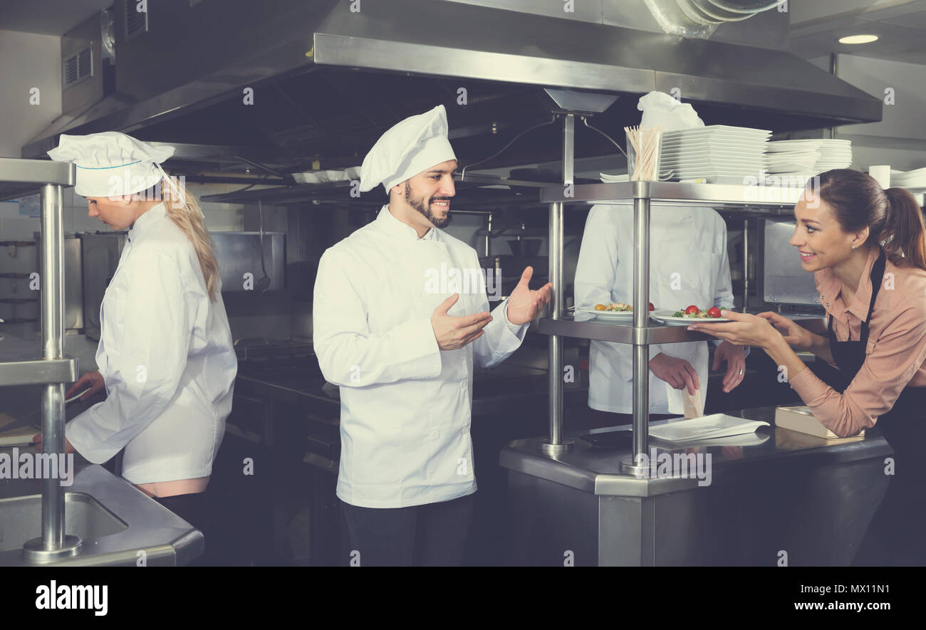 Personnel du restaurant avec jeune chef cuisinier travaillant ensemble dans la cuisine Banque D'Images