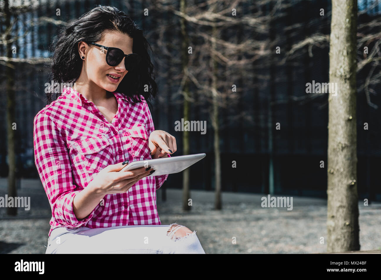 Heureux et belle jeune femme utilise le téléphone. Cute girl vérifie par SMS, email, à l'extérieur. Mode de vie, la joie de la vie. Femme bénéficie d'achats en ligne. Banque D'Images