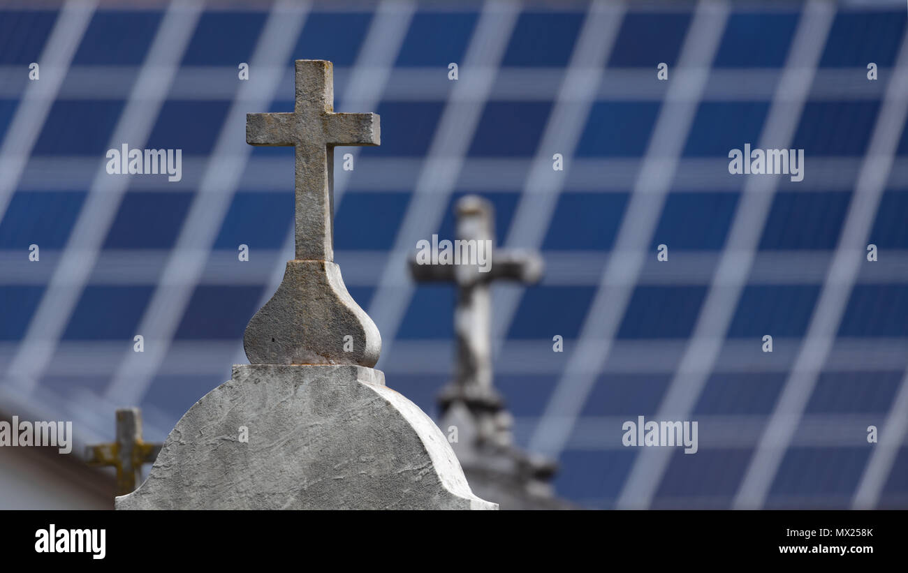 Croix en pierre sur les tombes avec panneaux solaires flou en arrière-plan Banque D'Images