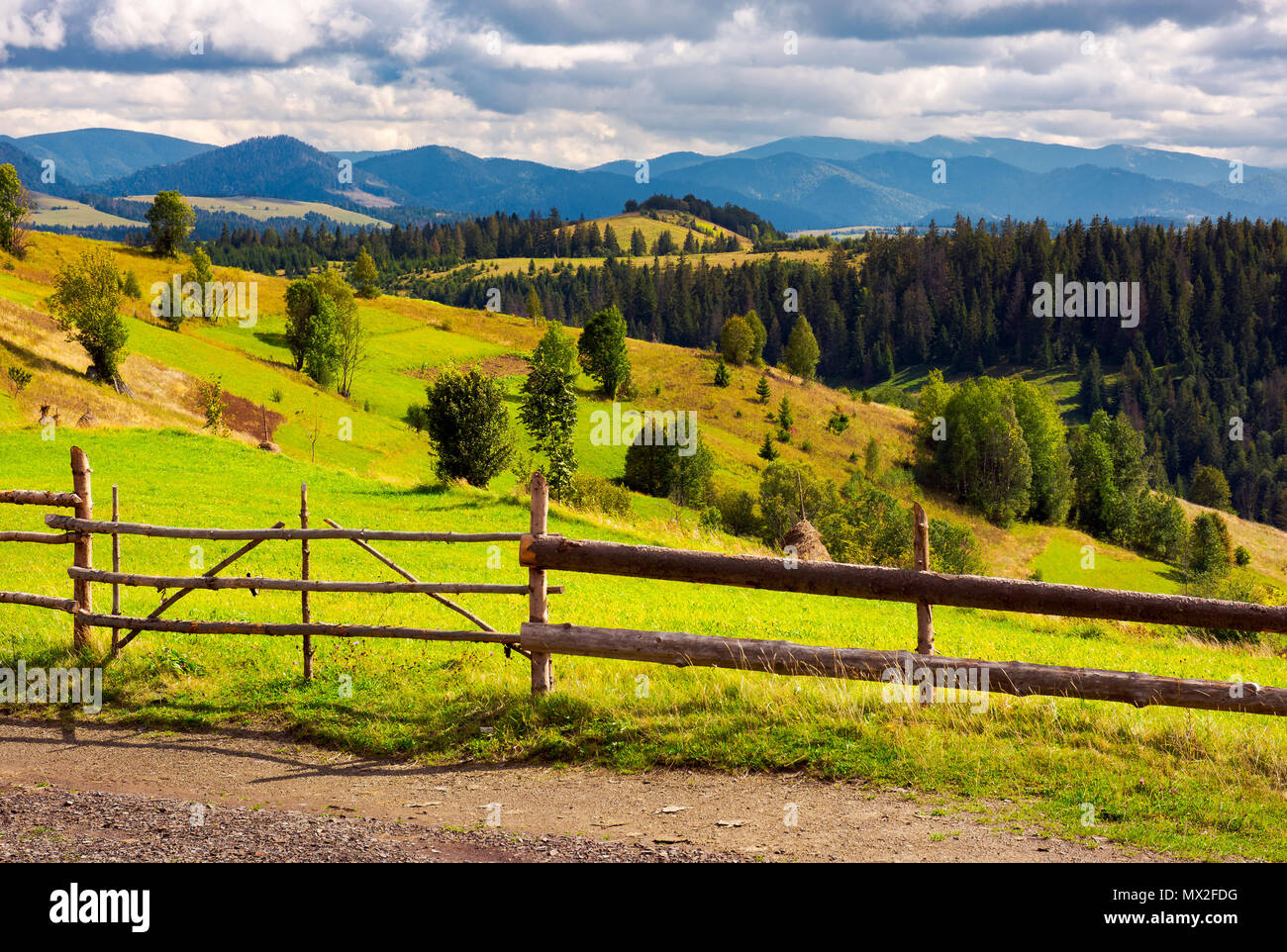 Clôture en face d'un des domaines ruraux sur collines. botte sur une pente herbeuse et crête de montagne dans la distance Banque D'Images